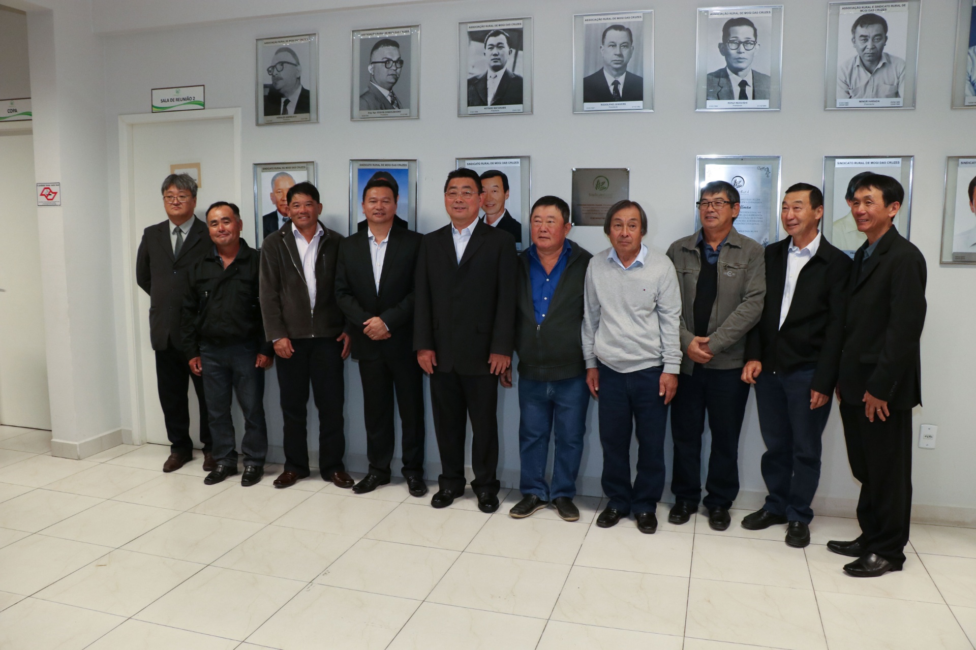Diretoria do Sindicato Rural de Mogi das Cruzes reunida na sede, à frente da galeria de ex-presidentes